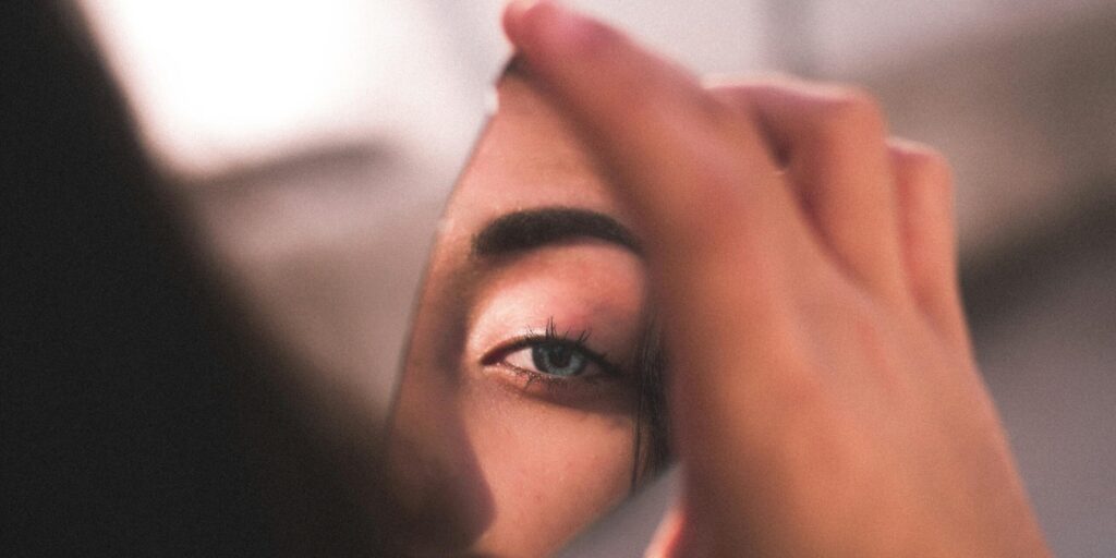 A captivating image of a woman's eye reflected in a broken mirror piece with soft lighting.