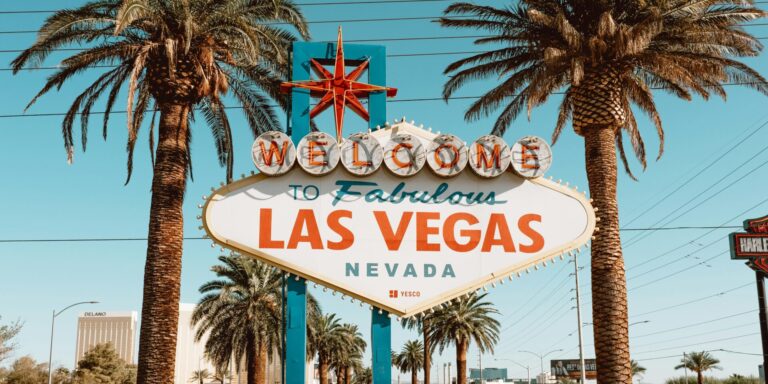 Capture of the famous Welcome to Las Vegas sign surrounded by palm trees under a clear blue sky.